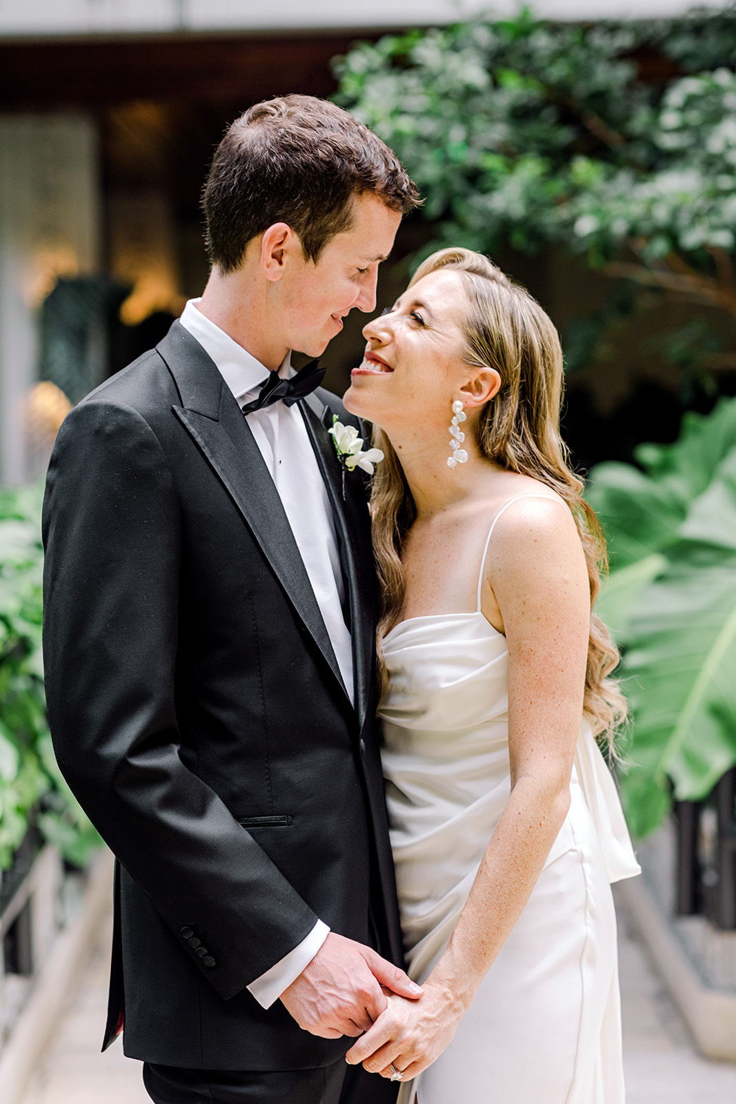 Bride and groom smile at each other for a candid portrait after first look at Mayfair House Hotel and Garden in Coconut Grove neighborhood of Miami, Florida. Elegant and modern wedding day photography by Tara Raftovich of Wedding by Tara.